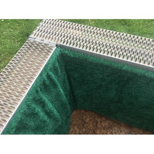 Die Grabmatte Typ Expander im Komplettset ist grün und weich, umschließt einen Erdbereich und hat eine silberne, perforierte Metallkante.