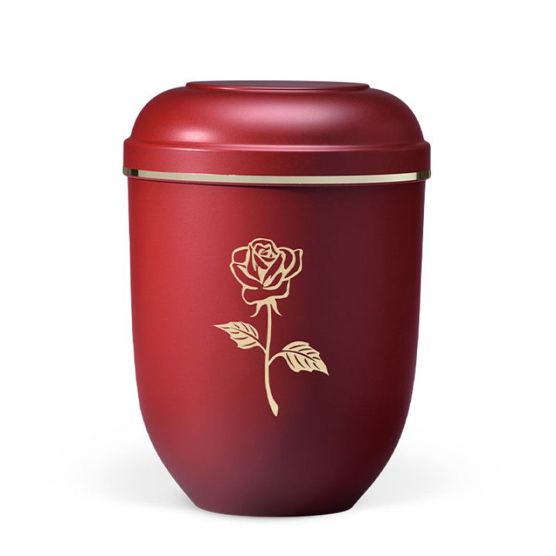 Die naturstoffurne ist weinrot matt, hat eine moderne Rosenabbildung in Gold und einen goldenen Rand am Deckel.