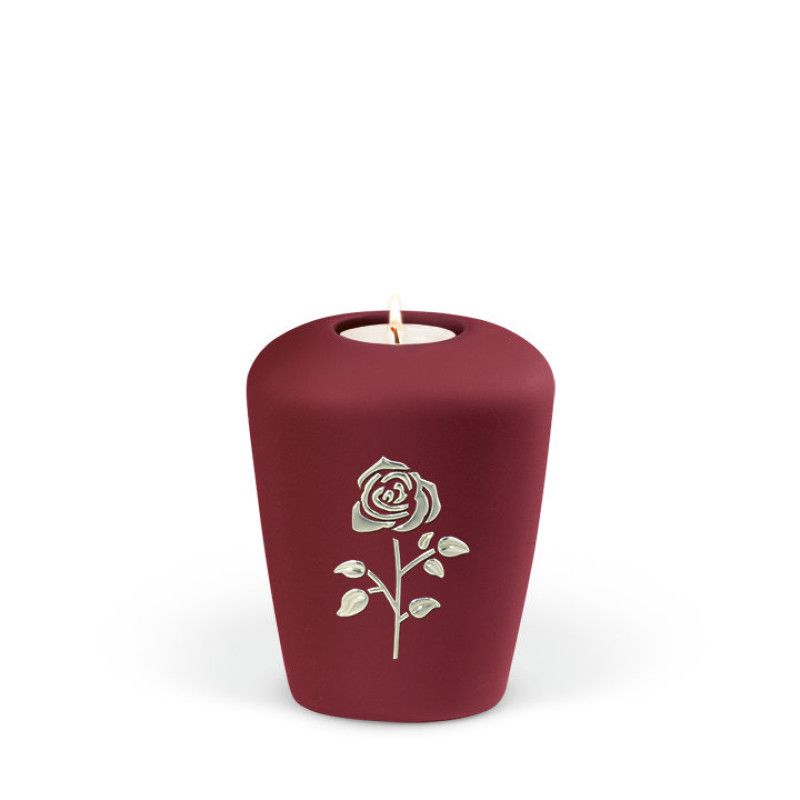 Weinrote Keramikurne in Form einer Gedenkurne mit einem Teelichthalter und einer silbernen Rosenmotivanbringung auf der Vorderseite.