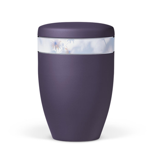 Die violette Naturstoffurne aus Velours hat eine runde Form und ein florales Dekorband, das sich um die Mitte der Urne zieht.
