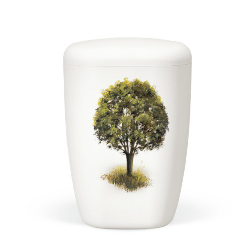 Eine weiße, matte Naturstoffurne mit handbemaltem Baum auf einer Wiese, in ovaler Form und mit einem leicht gewölbten Deckel.