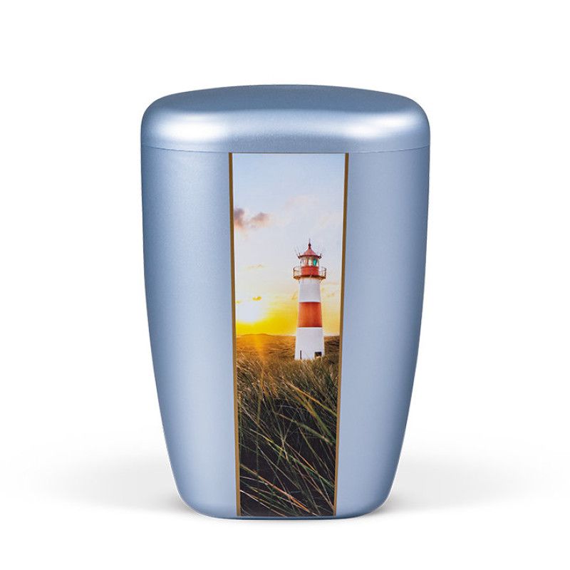 Die Naturstoffurne in Gletscherblau hat eine ovale Form und zeigt ein vertikales Dekor mit einem Leuchtturm auf einer Wiese.