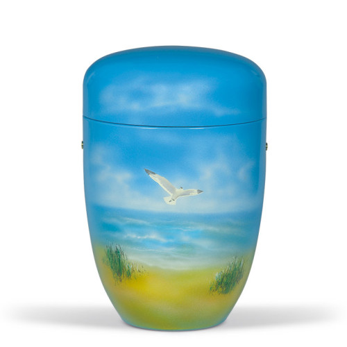 Die Himmelblaue Stahlurne hat eine ovale Form und zeigt ein Airbrush-Motiv einer Möwe vor einem sanften Himmel und einer Landschaft mit Gras.