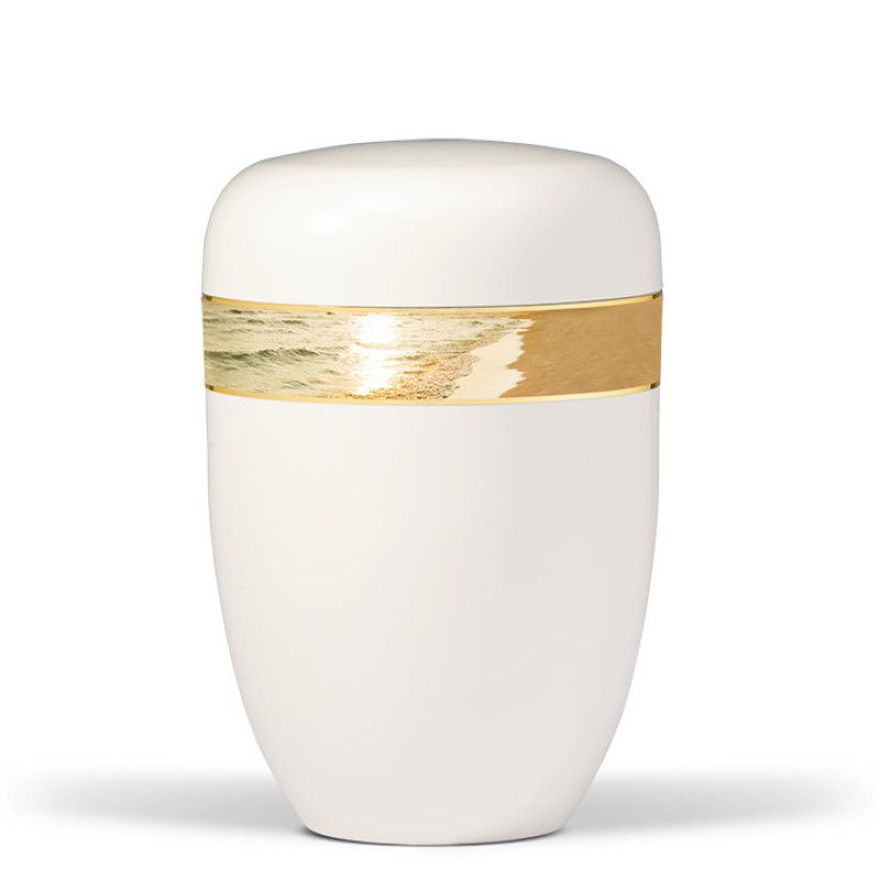 Die cremeweiße Stahlurne hat eine ovale Form und ist mit einem dekorativen Band in Gold und einem Strandmotiv verziert.