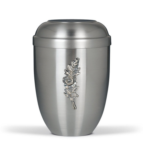 Stahlurne ZIHESTA in silber mit flachem Deckel und einer reliefartigen Rosenbund-Dekoration auf der Vorderseite, Gesamtansicht des Produkts.