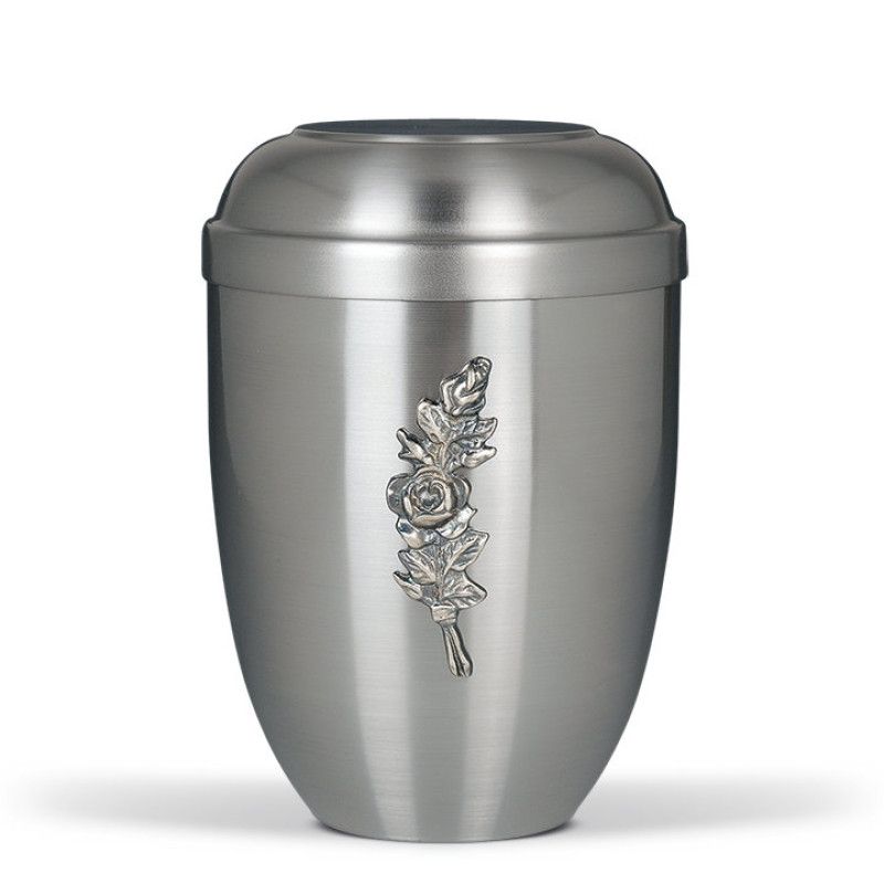 Stahlurne ZIHESTA in silber mit flachem Deckel und einer reliefartigen Rosenbund-Dekoration auf der Vorderseite, Gesamtansicht des Produkts.