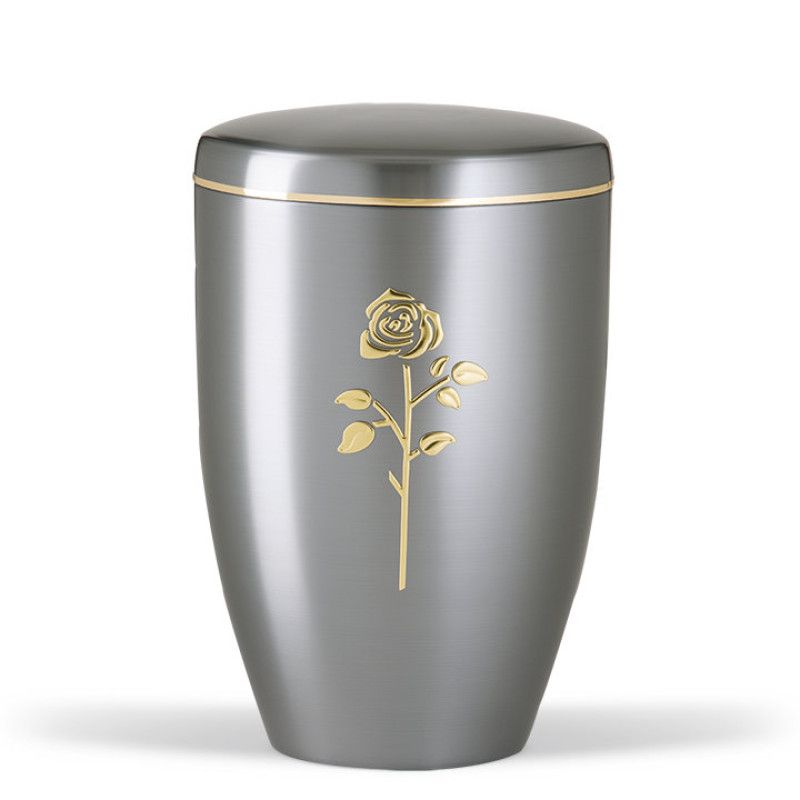 Die Stahlurne ZIHESTA ist silberfarben mit einer goldenen Rose und einem Goldband am oberen Rand, in einer Gesamtansicht dargestellt.