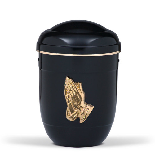 Schwarze Stahlurne mit polierten betenden Händen und einem goldenen Band, in runder Form mit einem geschlossenen Deckel, Gesamtansicht.