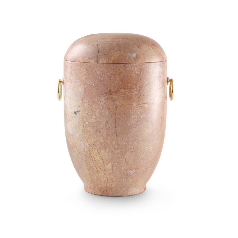 Die Urne aus rosa Marmor mit wenigen Einschlüsse ist gedreht und poliert, hat eine ovale Form und goldene Griffe an den Seiten.