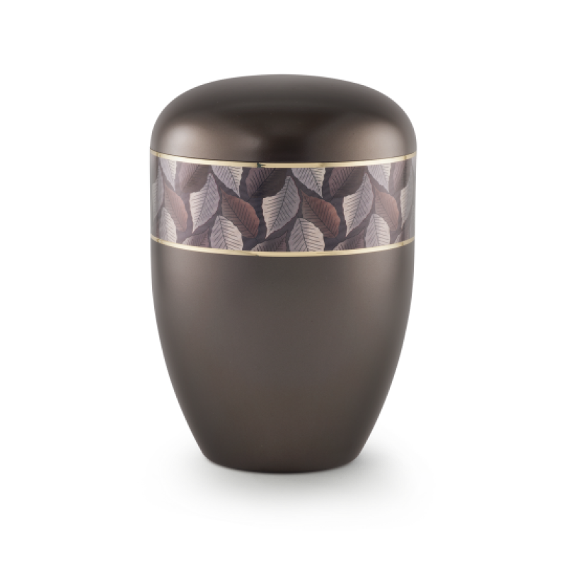 Die Urne in perlmutt chocolat hat eine ovale Form, ist aus einem biologisch abbaubaren Material gefertigt und besitzt ein Zierband mit Blattmotiv und Goldstreifen.