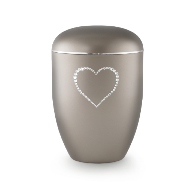 Die Urne der Edition Karat in perlmutt fumé hat eine ovale Form, einen glatten, matten Oberflächenfinish und ist mit einem Herz aus Kristallen verziert.