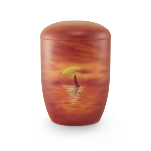 Die Urne aus Anhydrit-Tonolith hat eine ovale Form, ist in warmen Rottönen gehalten und zeigt ein Airbrushmotiv eines Segelbootes vor einem Sonnenuntergang.