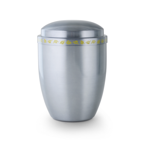 Die Urne Cestal ist aus satiniertem, getöntem Metall gefertigt, hat eine ovale Form und ist mit einem gelben Zierband verziert.