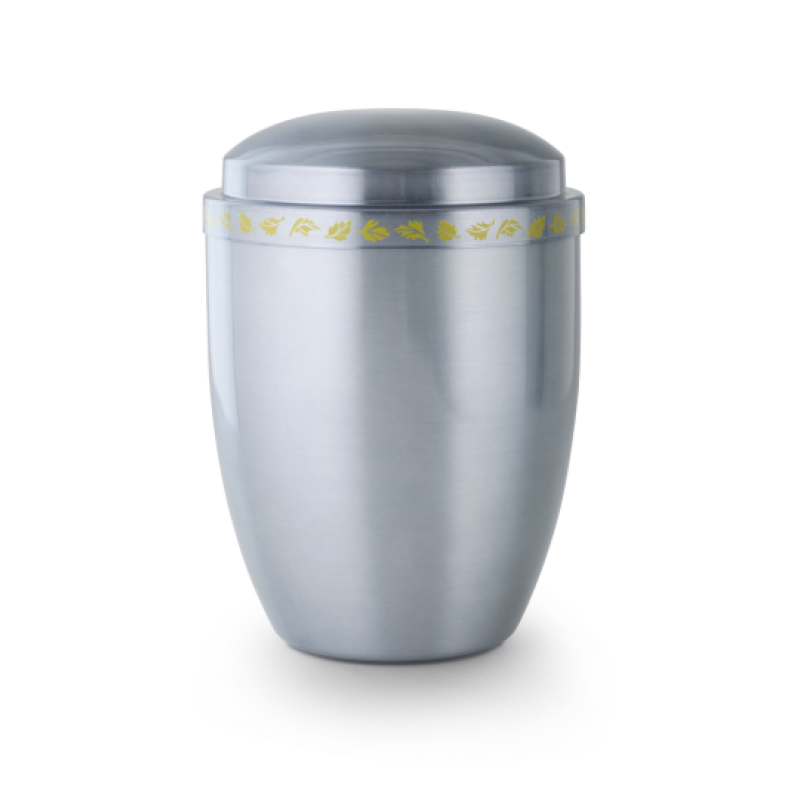 Die Urne Cestal ist aus satiniertem, getöntem Metall gefertigt, hat eine ovale Form und ist mit einem gelben Zierband verziert.