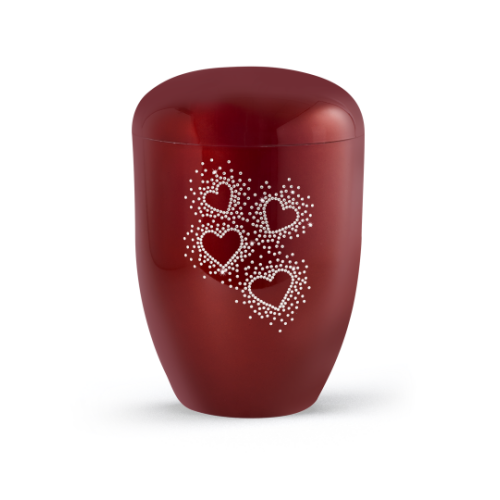 Die Urne der Edition Karat ist hochglanz rubinrot, hat eine ovale Form und zeigt auf der Vorderseite Herzen aus Kristallen sowie ein biol. abbaubares Material.