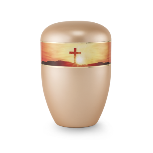 Die Urne in perlmutt apricot hat eine runde Form, einen glänzenden Deckel und einen dekorativen Streifen mit einem Kreuz vor einem Sonnenuntergang.