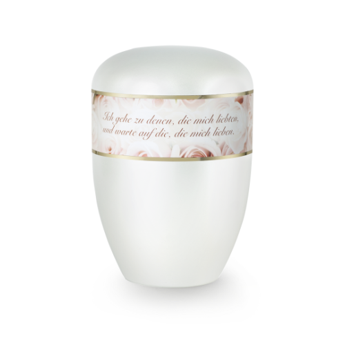 Die Urne in Perlmuttfarbe hat eine ovale Form, ist mit einem goldenen Rand und einer dekorativen Banderole mit Rosenmotiven sowie einem Trauerspruch versehen.