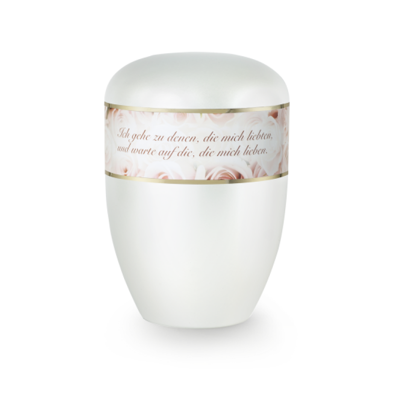 Die Urne in Perlmuttfarbe hat eine ovale Form, ist mit einem goldenen Rand und einer dekorativen Banderole mit Rosenmotiven sowie einem Trauerspruch versehen.