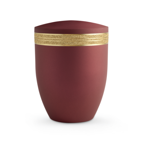 Die Urne der Edition Krypta in Samton Rubin hat eine matte, rotbraune Oberfläche und ist mit einem glitzernden, mattgoldenen Dekor verziert.