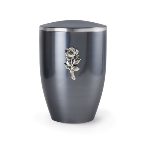 Die Urne der Edition Melina in dark moon lasiert hat eine ovale Form, ist aus Metall gefertigt und zeigt eine silberne Rose als Dekorationsdetail.