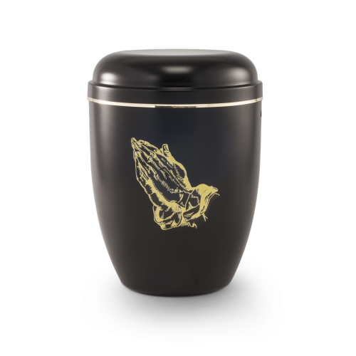 Die schwarze Urne aus Stahl hat eine runde Form, einen goldenen Streifen und zeigt betende Hände in goldener Farbe.