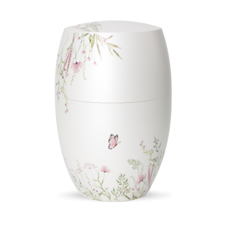 Die Urne aus der Edition Botanique ist in Perlmutt-Mattweiß gehalten und zeigt eine Blumenwiese in Rosa mit einem Schmetterling, in ovaler Form und Gesamtansicht.