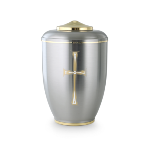Die Urne in silberner, polierter Metalloberfläche hat einen goldenen Deckel und ein zweifarbiges Kreuz auf der Vorderseite.