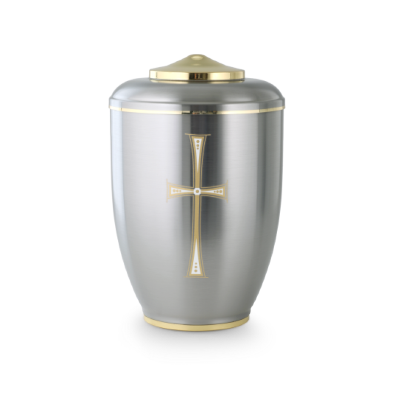 Die Urne in silberner, polierter Metalloberfläche hat einen goldenen Deckel und ein zweifarbiges Kreuz auf der Vorderseite.