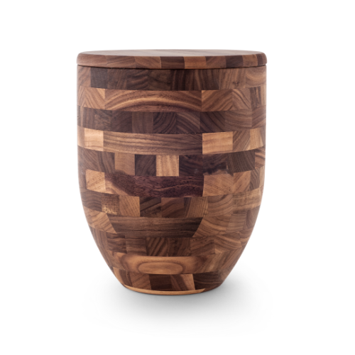 Die Urne der Edition Alea hat eine Vasenform, ist kreuzverleimt und besteht aus Holz mit einem geometrischen Muster in verschiedenen Brauntönen.