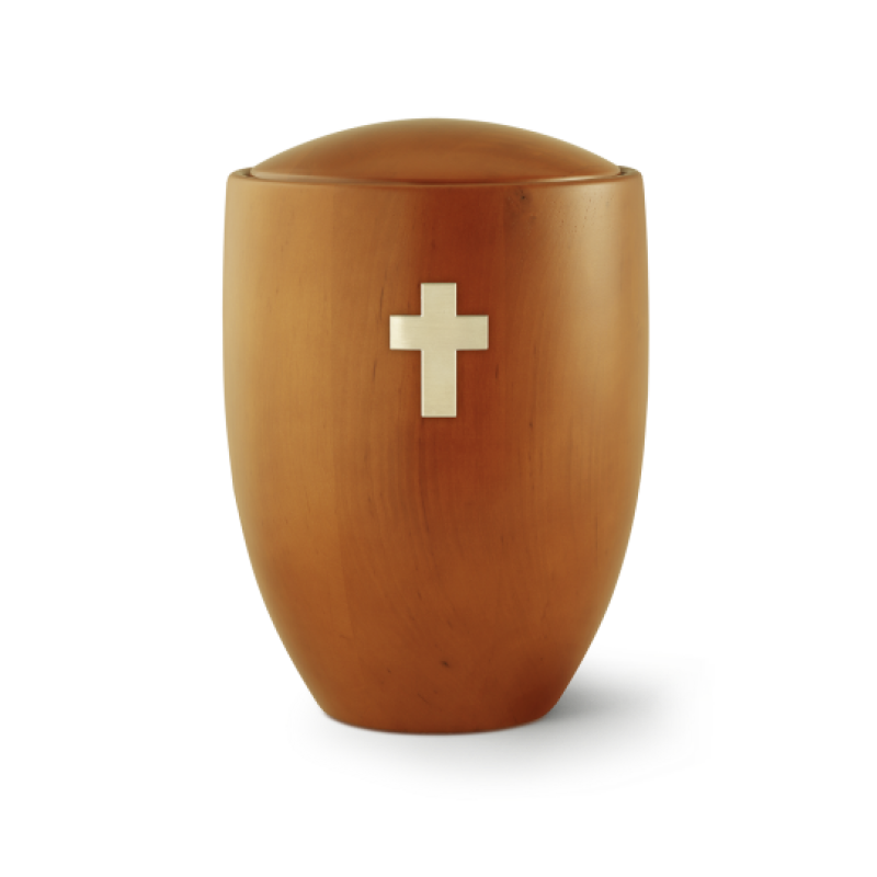 Die Urne der Edition Sevilla aus Erle und Mango hat eine ovale Form, ist in einem warmen Holzton gehalten und zeigt ein gebürstetes Messingkreuz auf der Vorderseite.