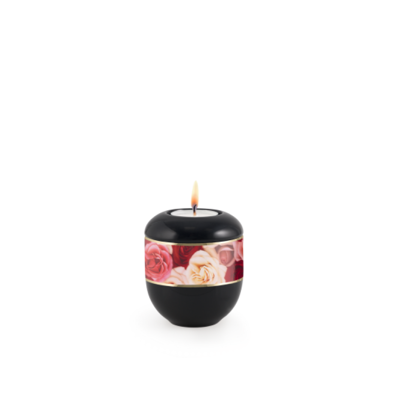 Gedenklicht in schwarz mit einem dekorativen Rosenmotiv und goldfarbener Umrandung, runde Form, Gesamtansicht mit brennender Kerze.