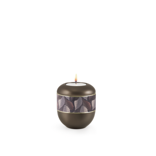 Gedenklicht in Form einer runden Urne, perlmutt chocolat mit einem Feuille-Zierband und Goldstreifen, brennend, Gesamtansicht.