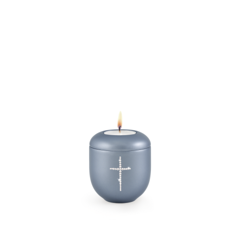 Gedenklicht in perlmutt stahlgrau mit einem Kreuz aus Kristallen, runde Form und leicht gewölbter Oberfläche, mit brennender Kerze oben.
