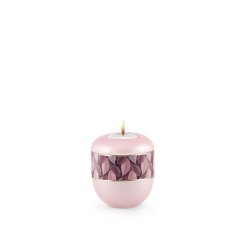 Gedenklicht in perlmutt rosé mit einer runden, glatten Form, verziert mit einem Feuille-Zierband und einem goldenen Streifen, Gesamtansicht mit brennender Kerze.