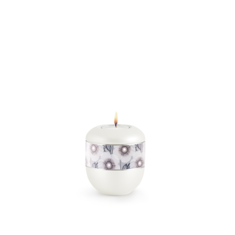 Gedenklicht in perlmuttfarbener Ausführung mit Blumen-Dekor und feinen Kristallen, abgerundete Form, Gesamtansicht mit brennender Flamme.