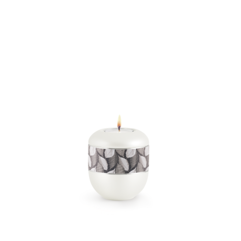 Gedenklicht aus der Edition Wave in perlmuttfarben mit einem Feuille-Zierband und Silberstreifen, in runder Form mit brennender Kerze oben.