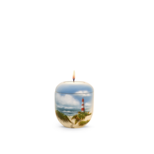 Gedenklicht in Form einer Urne mit einem Leuchtturm-Motiv, blauer Oberseite und sandfarbener Unterseite, mit einer brennenden Kerze oben.