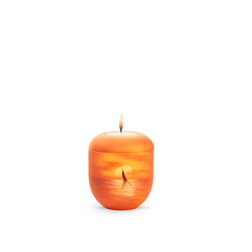 Eine orangefarbene Gedenklicht-Urne in runder Form mit einem Segelboot-Motiv und einer brennenden Kerze auf der Oberseite.