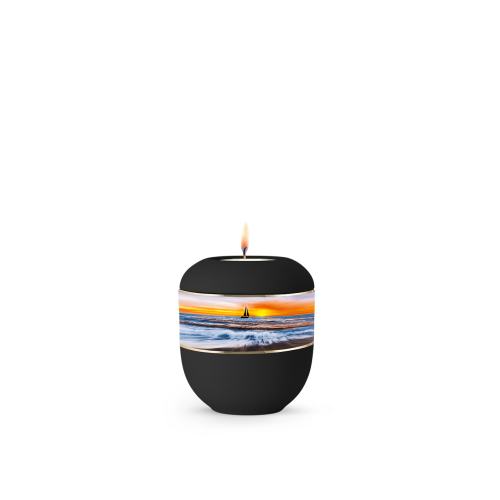 Die schwarze Urne aus Porzellan in runder Form zeigt ein Segelboot auf einem bunten, maritimen Motiv und hat eine flamme, die oben sichtbar ist.