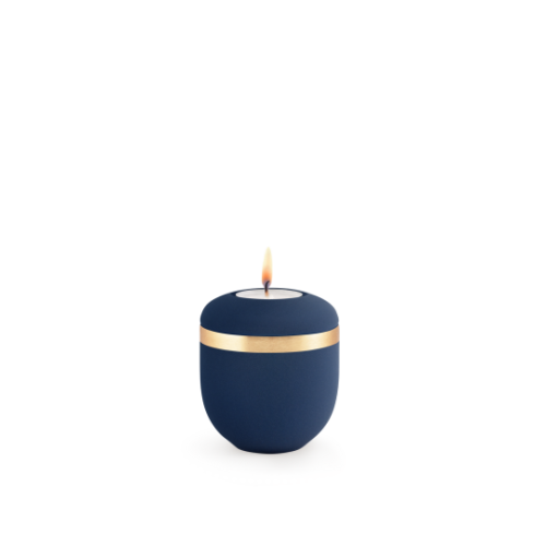 Ein rundes, mattes Gedenklicht in Marineblau mit einem gebürsteten Goldband, das eine Flamme in der Mitte zeigt.