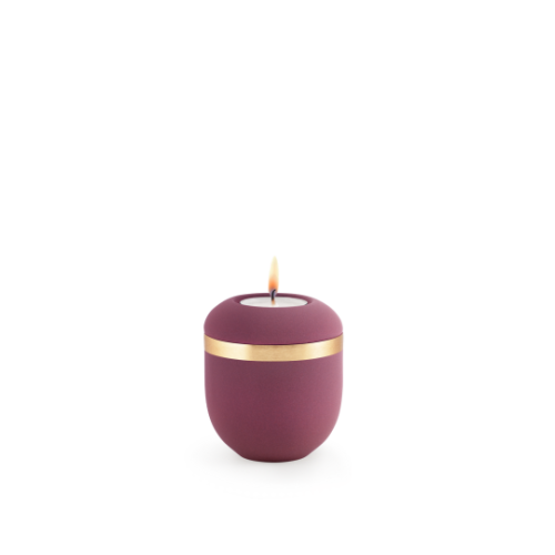 Gedenklicht aus der Edition Xenon in Samton Burgund mit einem gebürsteten Goldband, runde Form und brennender Flamme, Gesamtansicht.