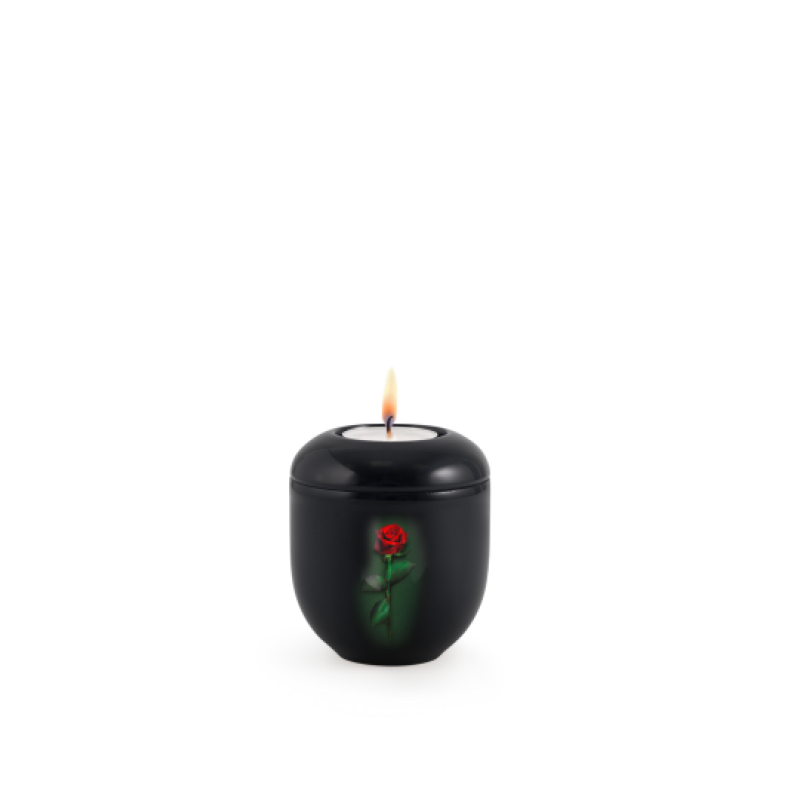 Gedenklicht aus schwarzem Klavierlack mit einer roten Rose auf der Vorderseite, in runder Form und mit brennender Kerze im Inneren.
