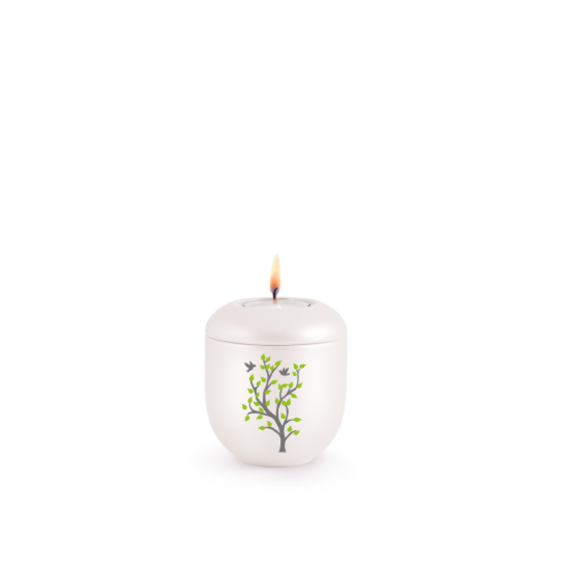 Gedenklicht aus der Edition Silva in perlmuttfarben mit einem Frühlingsbaum-Motiv in Grün und Schwarz, Gesamtansicht mit brennender Flamme.