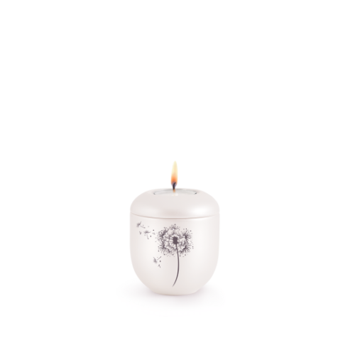 Ein rundes, perlmuttfarbenes Gedenklicht mit einer schwarzen Pusteblume und hochwertigen Kristallen, in Gesamtansicht mit brennender Flamme oben.
