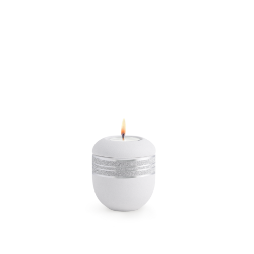 Gedenklicht aus mattsilbernem Samton mit glitzerndem Dekor, rundliche Form, sichtbare Flamme, Gesamtansicht.