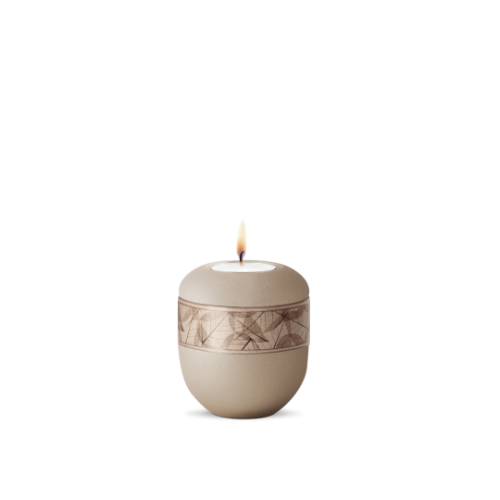 Gedenklicht aus der Edition Papyrus in velvet champagner mit Blätterdekor, rundliche Form und flammender Kerze oben, Gesamtansicht.