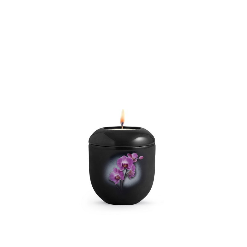 Gedenklicht in Klavierlack schwarz mit einer Orchideen-Dekoration, runde Form, brennende Flamme auf der Oberseite, Gesamtansicht des Produkts.