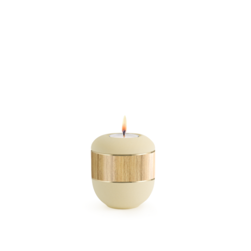 Gedenklicht in Samtton creme mit dekorativer, holzähnlicher Bandapplikation, rundliche Form und brennender Flamme, Gesamtansicht.