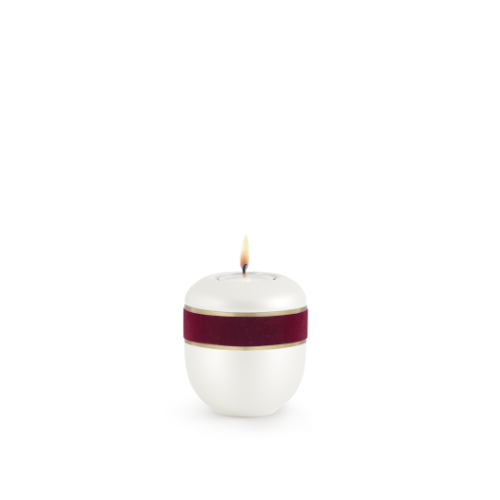 Ein Gedenklicht aus Perlmutt mit bordeauxfarbenem Dekor und goldener Verzierung, in runder Form mit einer Flamme auf der Oberseite.