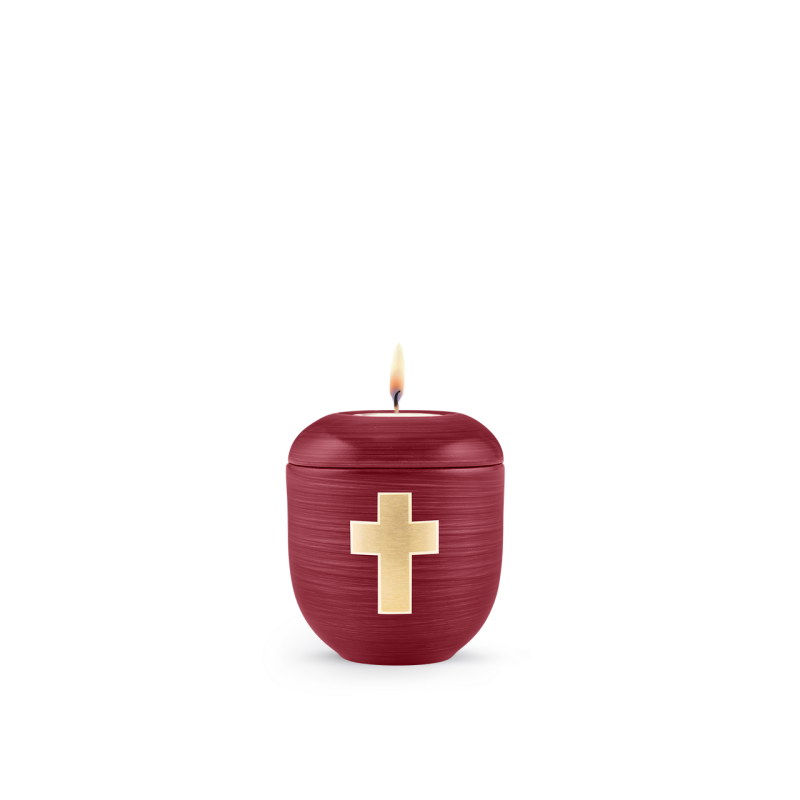 Gedenklicht in Florentinerrot, handbemalt, mit gebürstetem Kreuz aus goldfarbenem Material, runde Form, Gesamtansicht mit brennender Kerze.